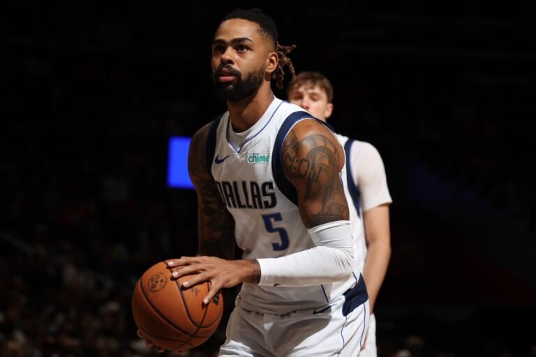 D’Angelo Russell holds a basketball in a Dallas Mavericks uniform.