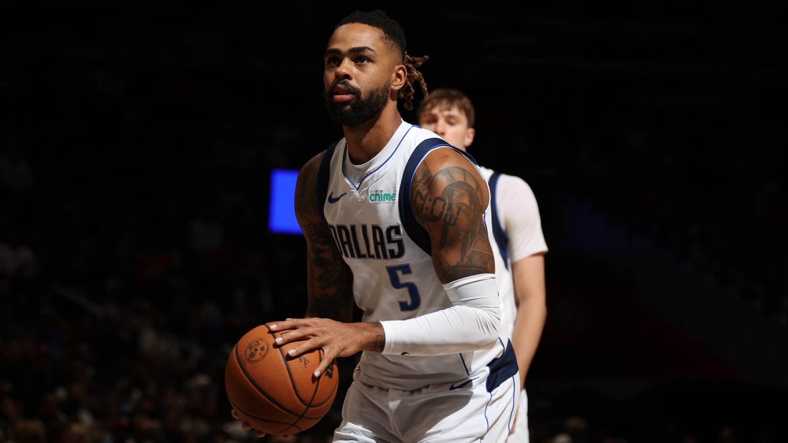 D’Angelo Russell holds a basketball in a Dallas Mavericks uniform.