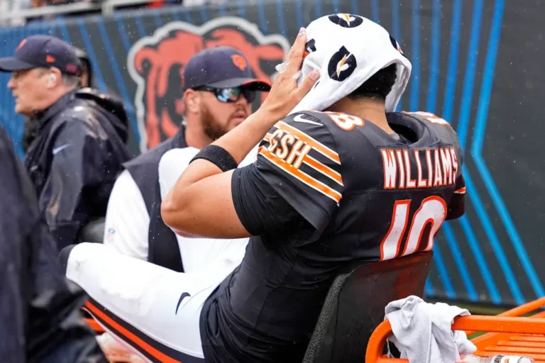 Caleb Williams holds a towel over his head on the sideline after leaving the Bears–Vikings game.