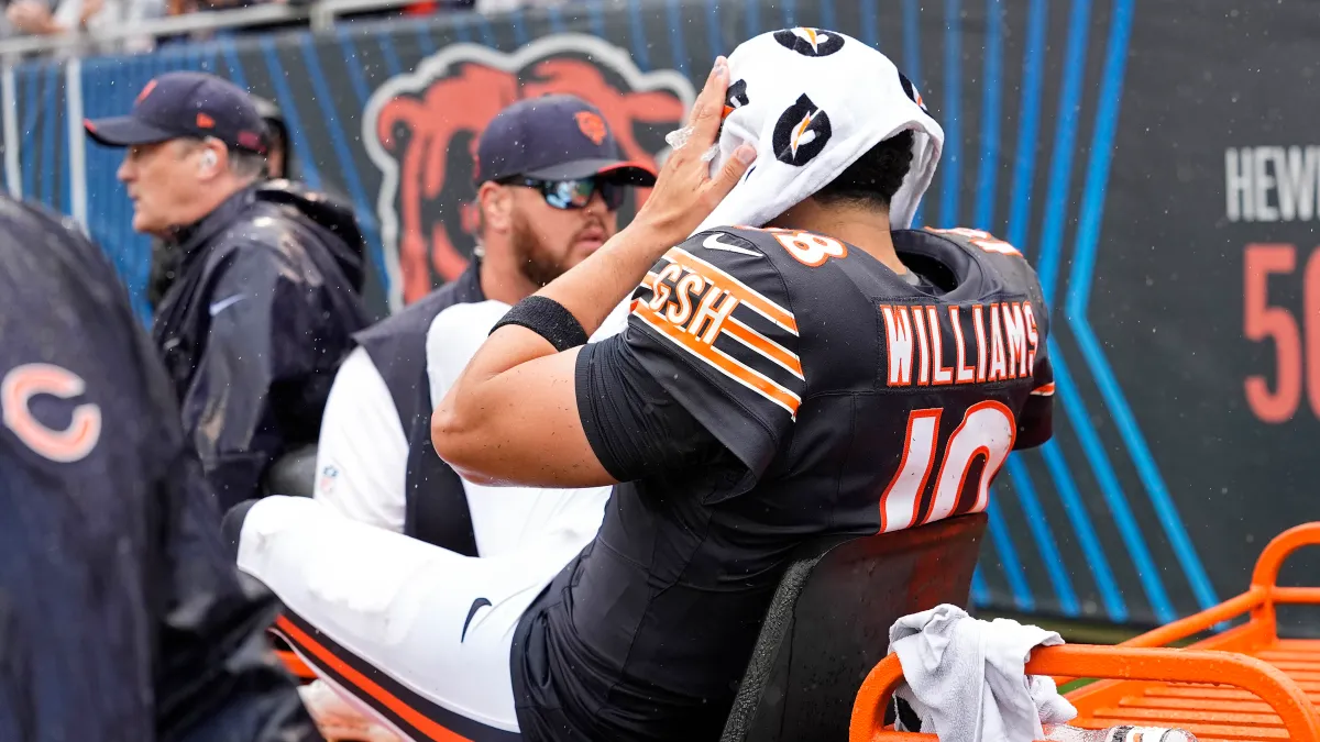 Caleb Williams holds a towel over his head on the sideline after leaving the Bears–Vikings game.