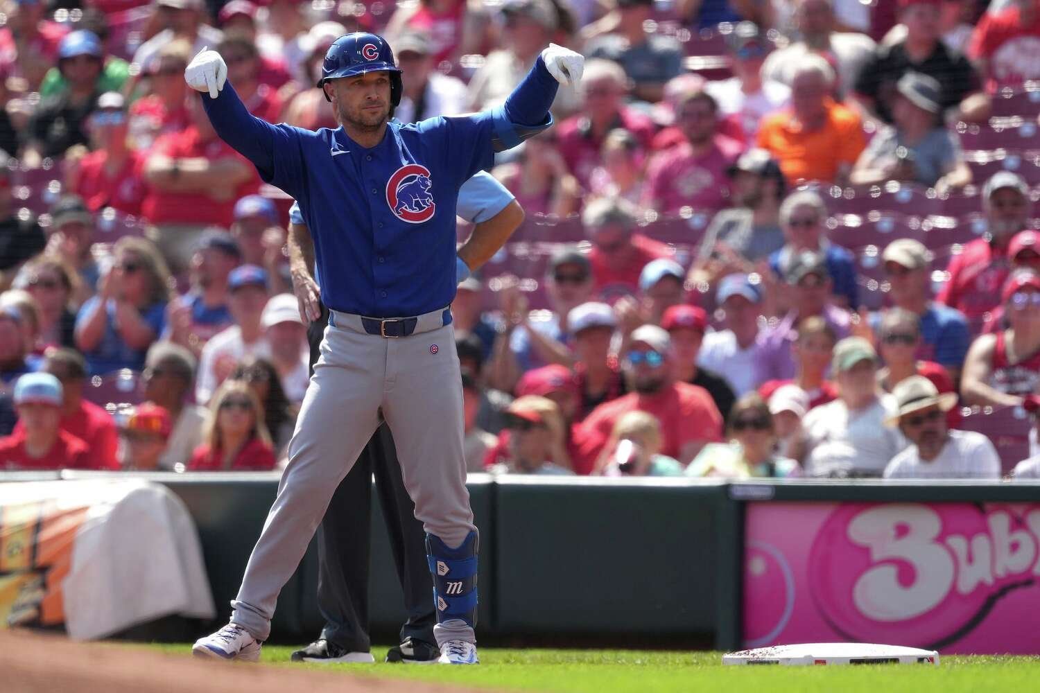 Alex Bregman in a blue Cubs uniform celebrates beside a base in Cincinnati.