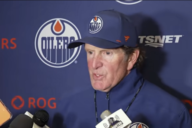 Mike Babcock speaks to reporters in front of an Edmonton Oilers backdrop.