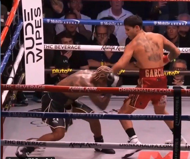 Ryan Garcia throws a punch as Conor Benn bends low near the ropes.