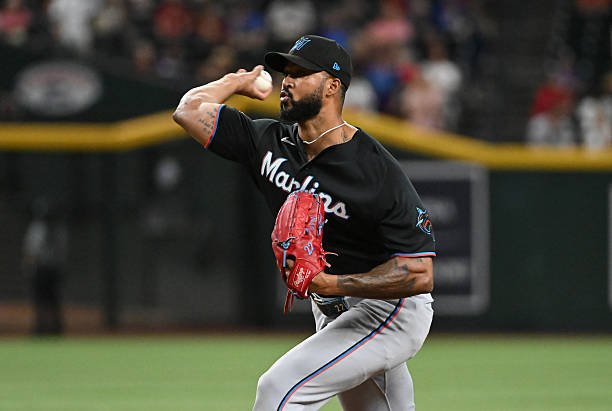 Sandy Alcantara delivers a pitch in a black Miami Marlins jersey, with his red glove in front of his chest.