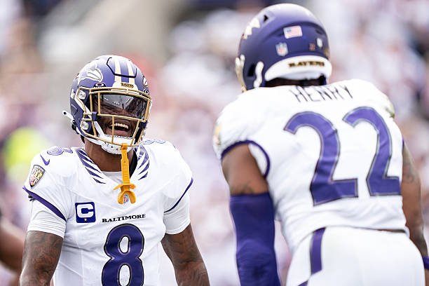 Lamar Jackson and Derrick Henry in white Ravens uniforms celebrate Henry’s touchdown against the Saints.