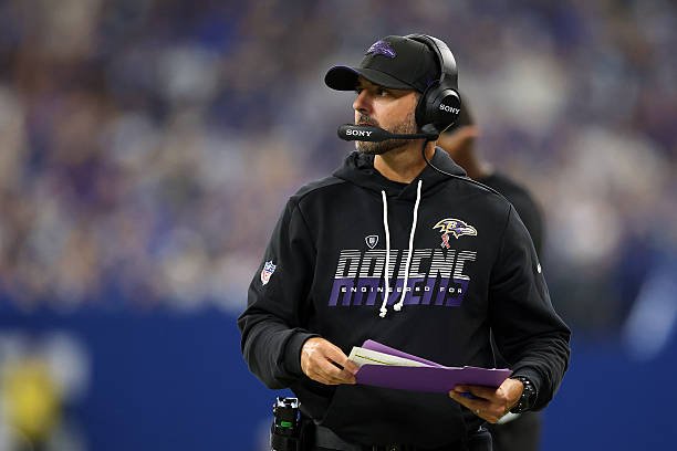 Baltimore Ravens head coach Jesse Minter watches from the sideline while holding his play sheet.