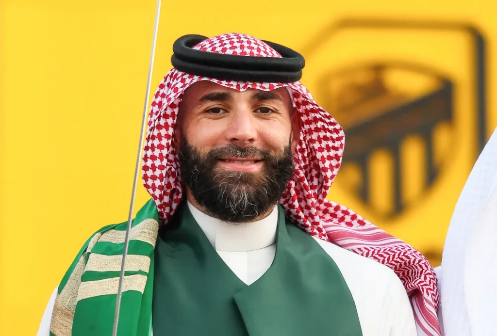 Karim Benzema smiling in traditional Saudi attire in an archival photograph.