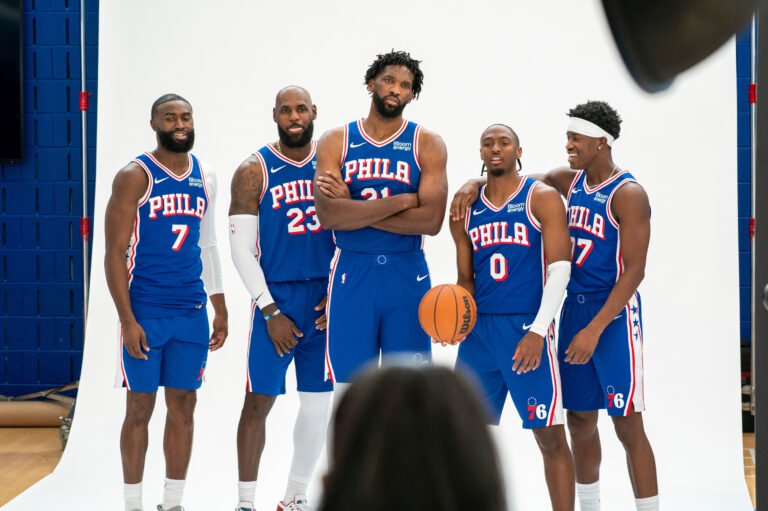 Jaylen Brown, LeBron James, Joel Embiid, Tyrese Maxey and VJ Edgecombe pose in blue Sixers uniforms at media day.
