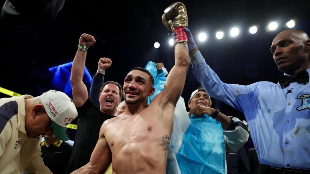 Teofimo López raises his gloved hand after a boxing match.