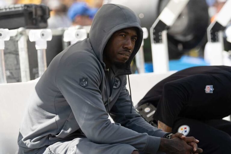 Joey Porter Jr. sits on the Steelers sideline wearing a gray hooded sweatshirt.