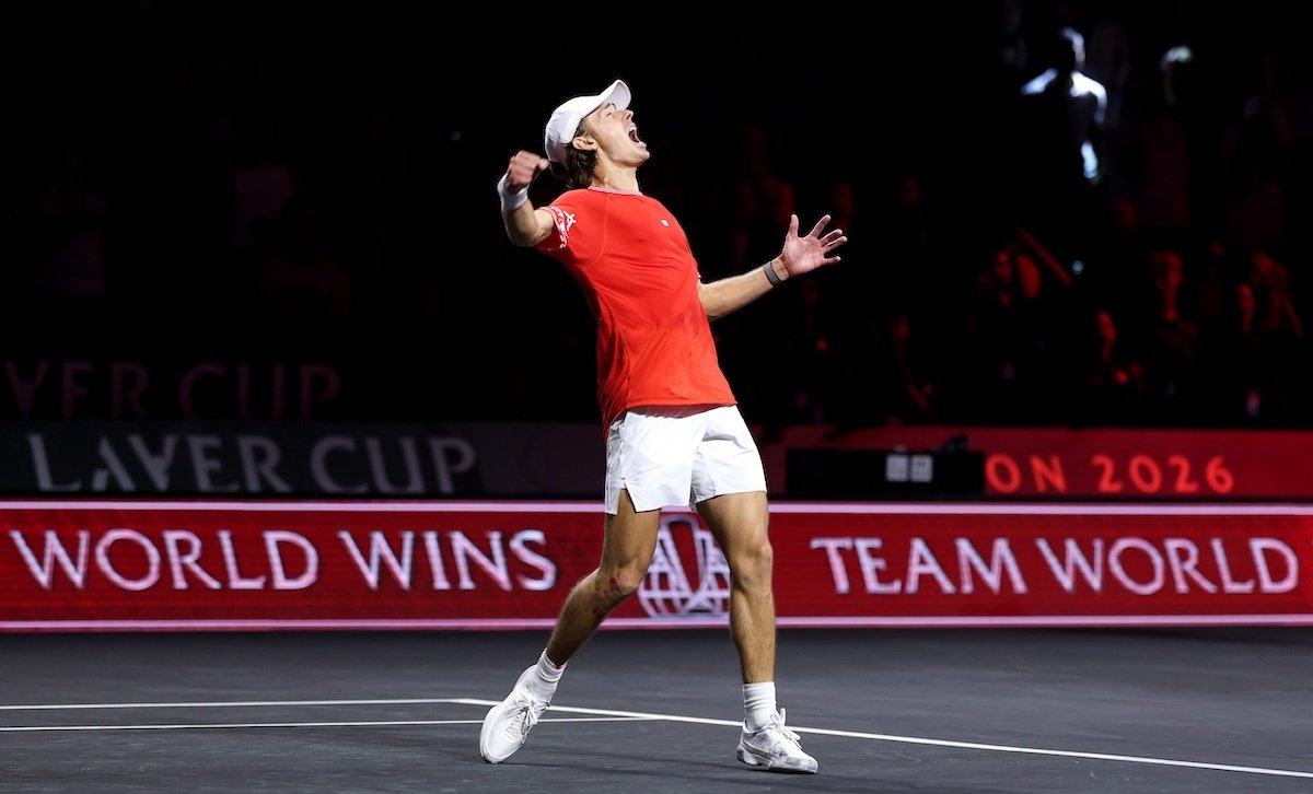 Alex de Minaur celebrates on court in his red Team World shirt.