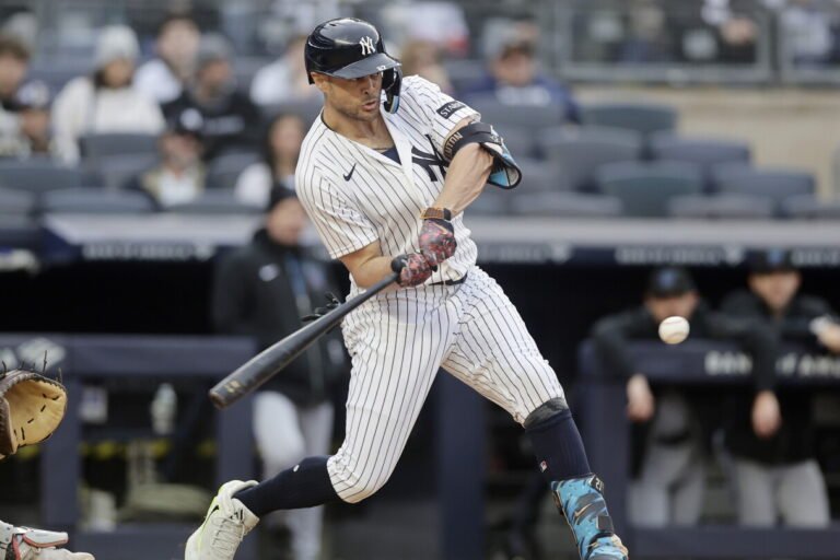Aaron Judge swings a bat in a Yankees home uniform.