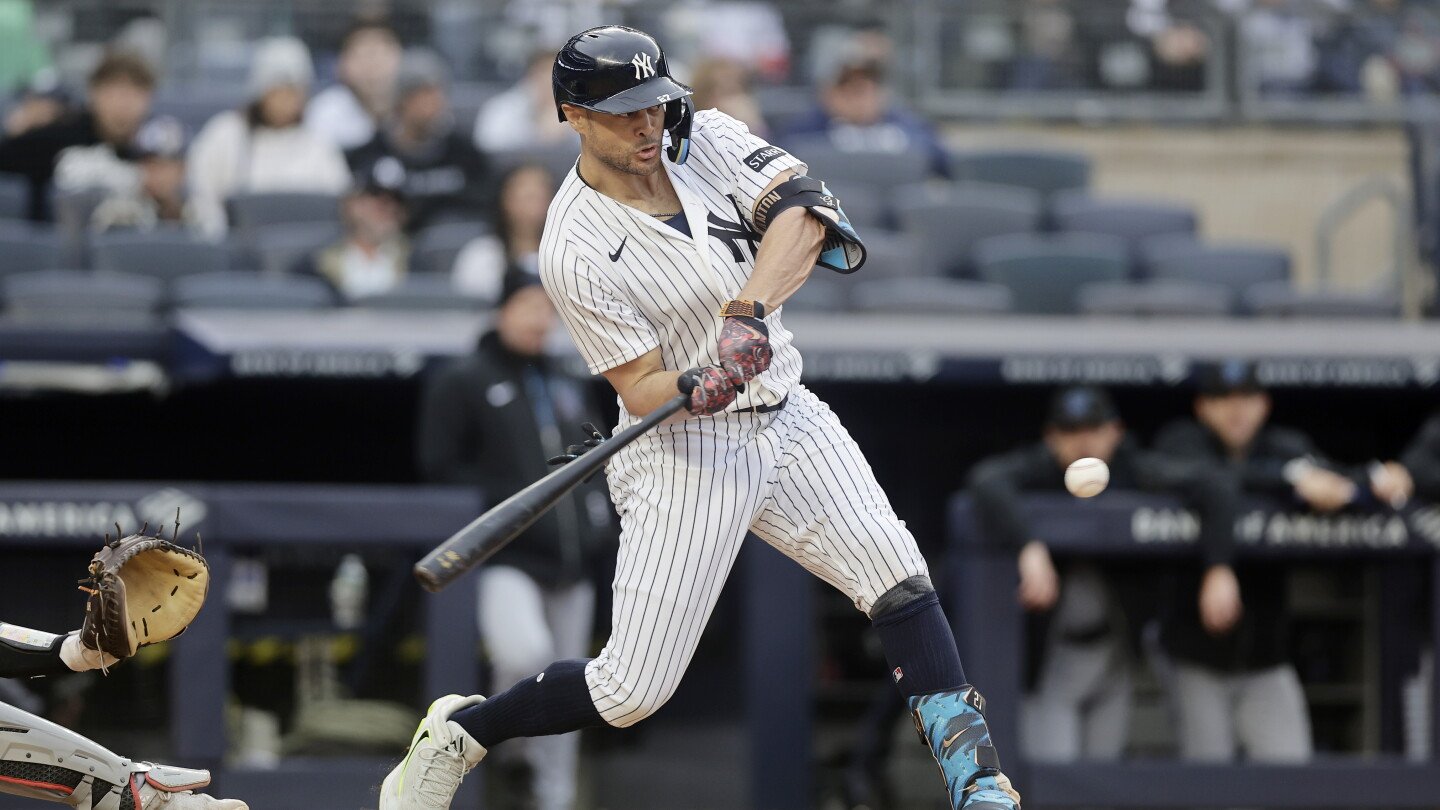 Aaron Judge swings a bat in a Yankees home uniform.