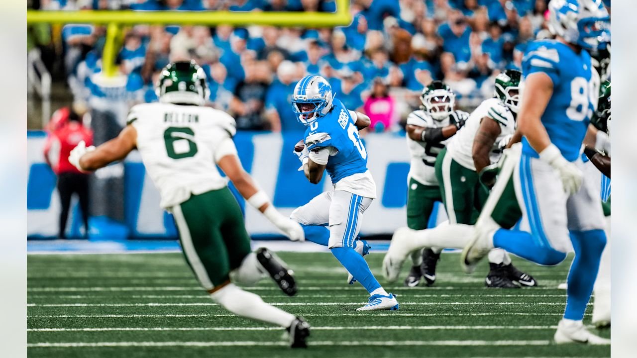 Jahmyr Gibbs runs with the ball as Jets defenders close in at Ford Field.