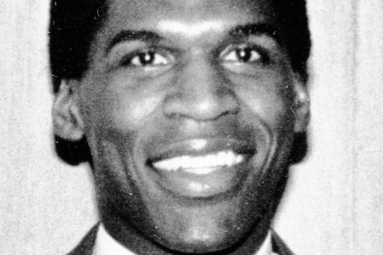 Robert Parish smiling in a suit and tie in a black-and-white archival portrait