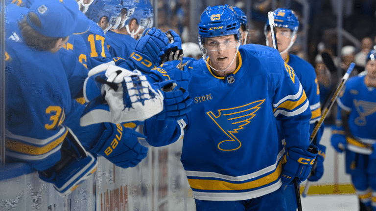 St. Louis Blues players celebrate beside their bench.