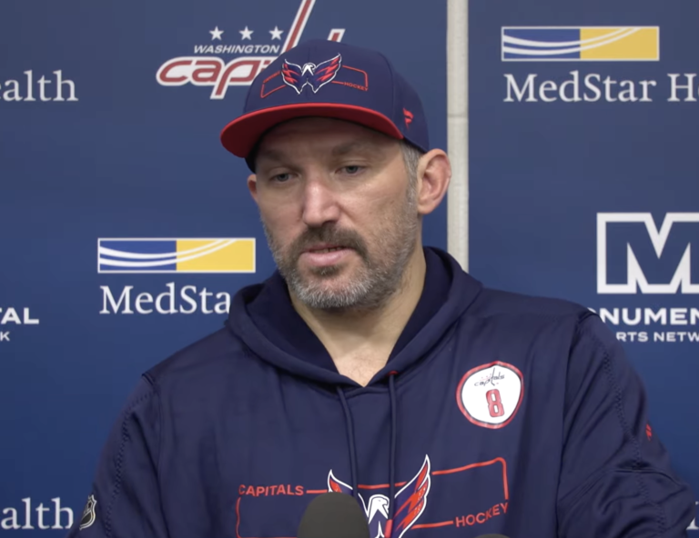 Alex Ovechkin wears a Capitals cap and hoodie while speaking to reporters.