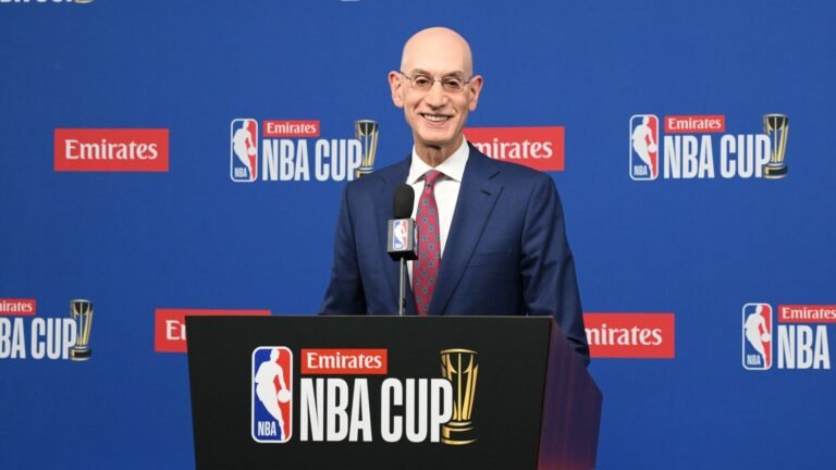 Adam Silver speaking behind an NBA Cup podium, with his head, shoulders and torso visible against the blue event backdrop.
