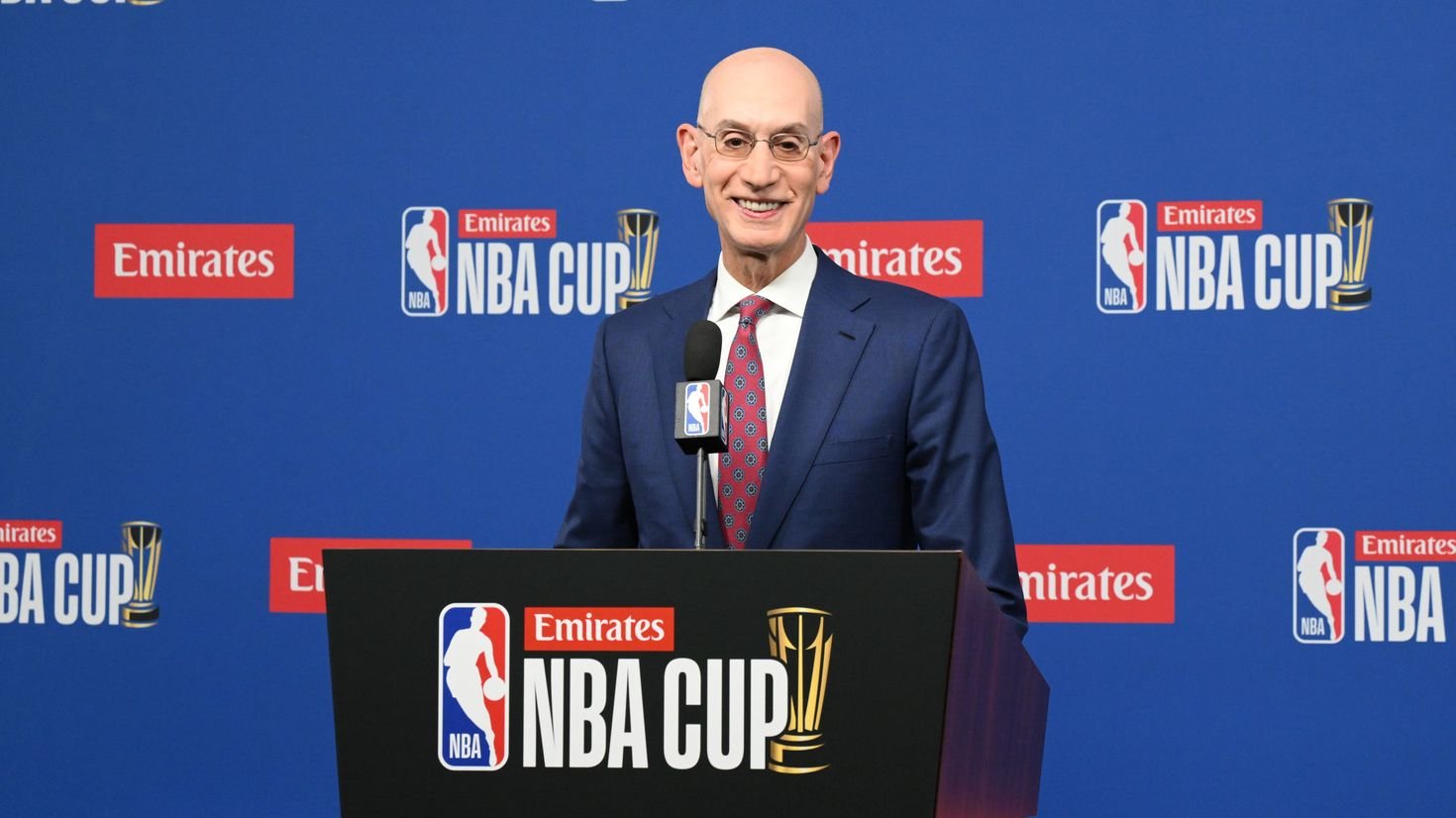 Adam Silver speaking behind an NBA Cup podium, with his head, shoulders and torso visible against the blue event backdrop.