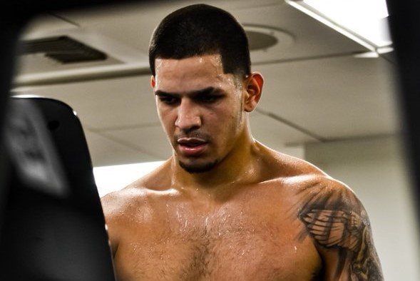 Edgar Berlanga wearing boxing gloves in a training gym.