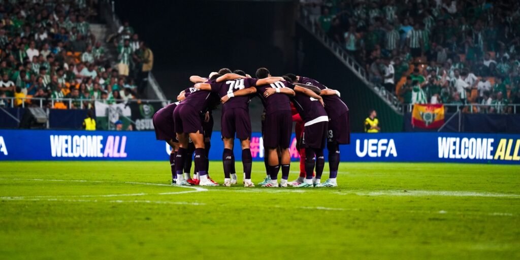 Porto players huddle in purple kits at La Cartuja, with Betis supporters behind them.
