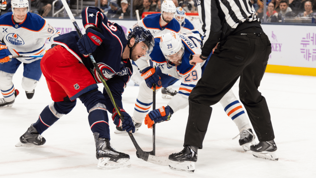 Columbus Blue Jackets and Edmonton Oilers players take a faceoff.