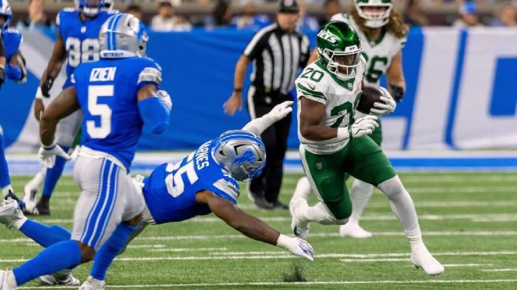Breece Hall runs with the ball as Detroit defenders close in at Ford Field.
