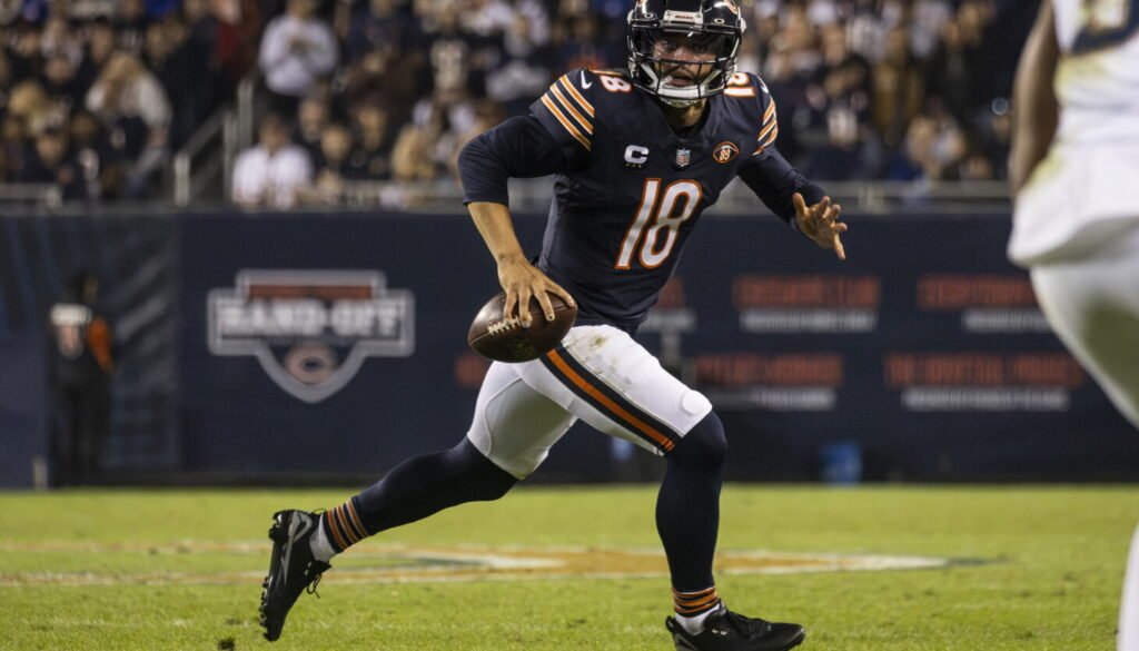 Caleb Williams runs with the football in black cleats against New England at Soldier Field.