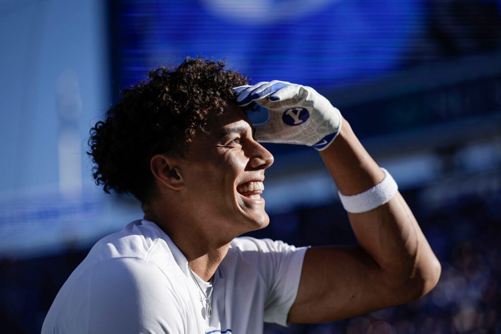 A smiling BYU player shading his eyes with a BYU glove.