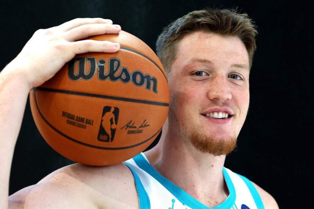 Kon Knueppel holds a basketball beside his face at Charlotte Hornets Media Day.