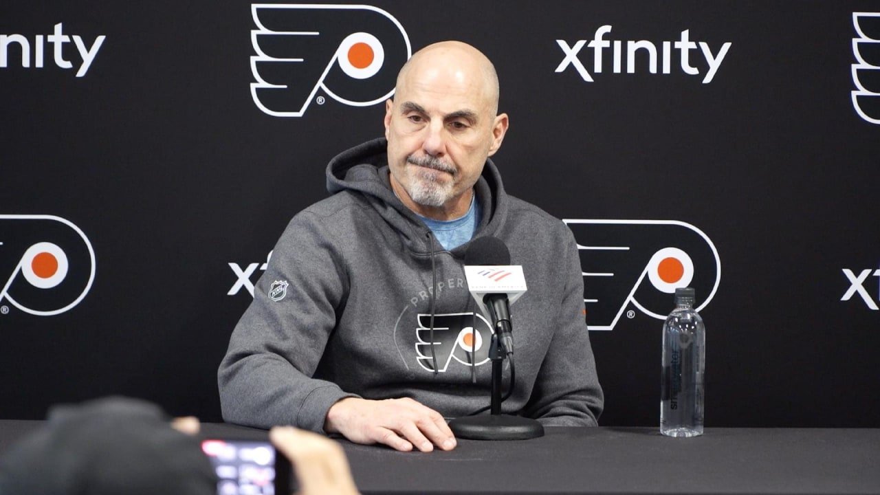 Rick Tocchet sits at a microphone in front of a Flyers backdrop after practice on October 18, 2026.