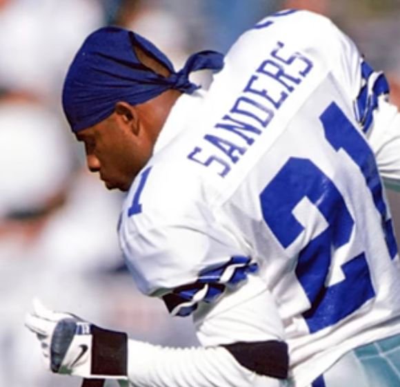 Deion Sanders wearing a white Dallas Cowboys number 21 uniform.