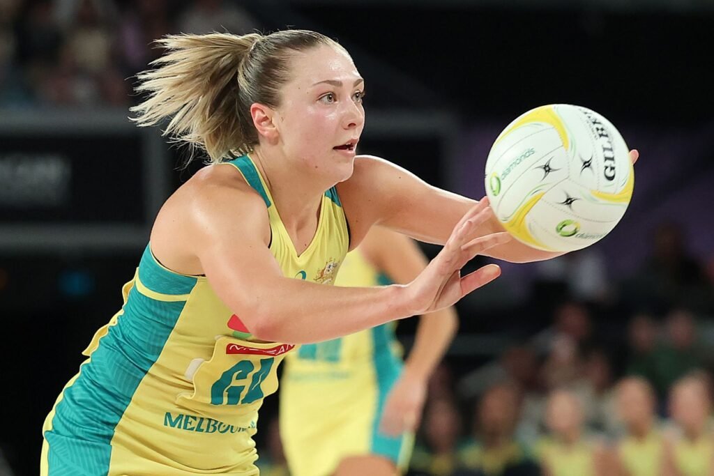 Georgie Horjus holds the netball in Australia’s green and gold uniform.