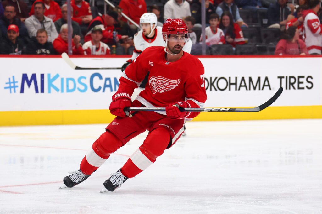 Dylan Larkin skates up the ice in a red Detroit Red Wings uniform.