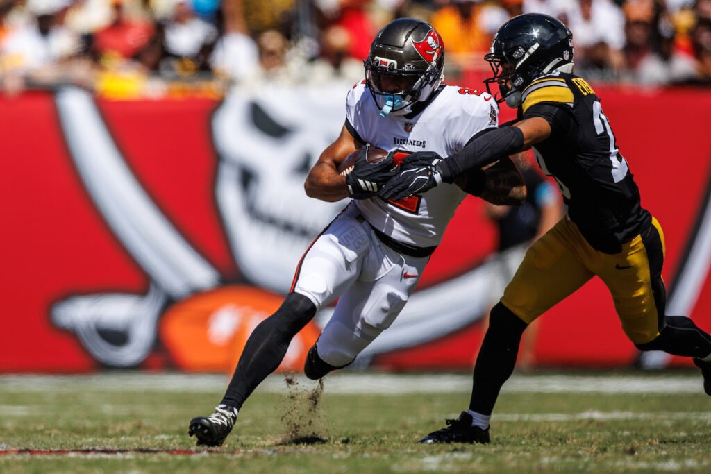 Emeka Egbuka carries the ball while a Pittsburgh defender reaches for him.