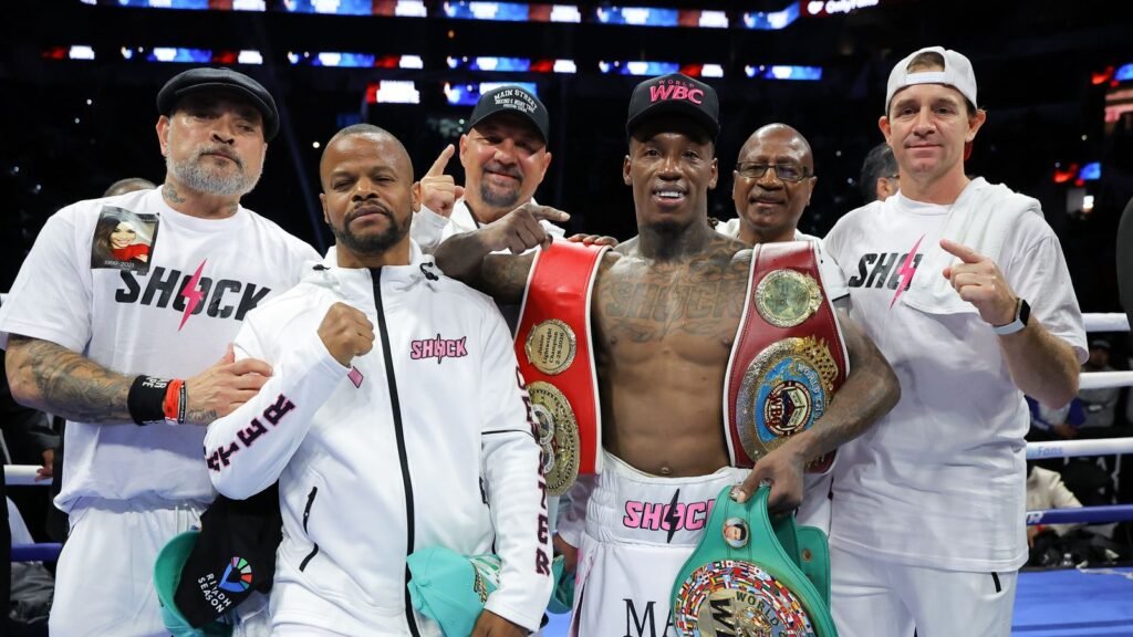 O’Shaquie Foster wearing championship belts alongside his team after the Navarrete fight in San Antonio.