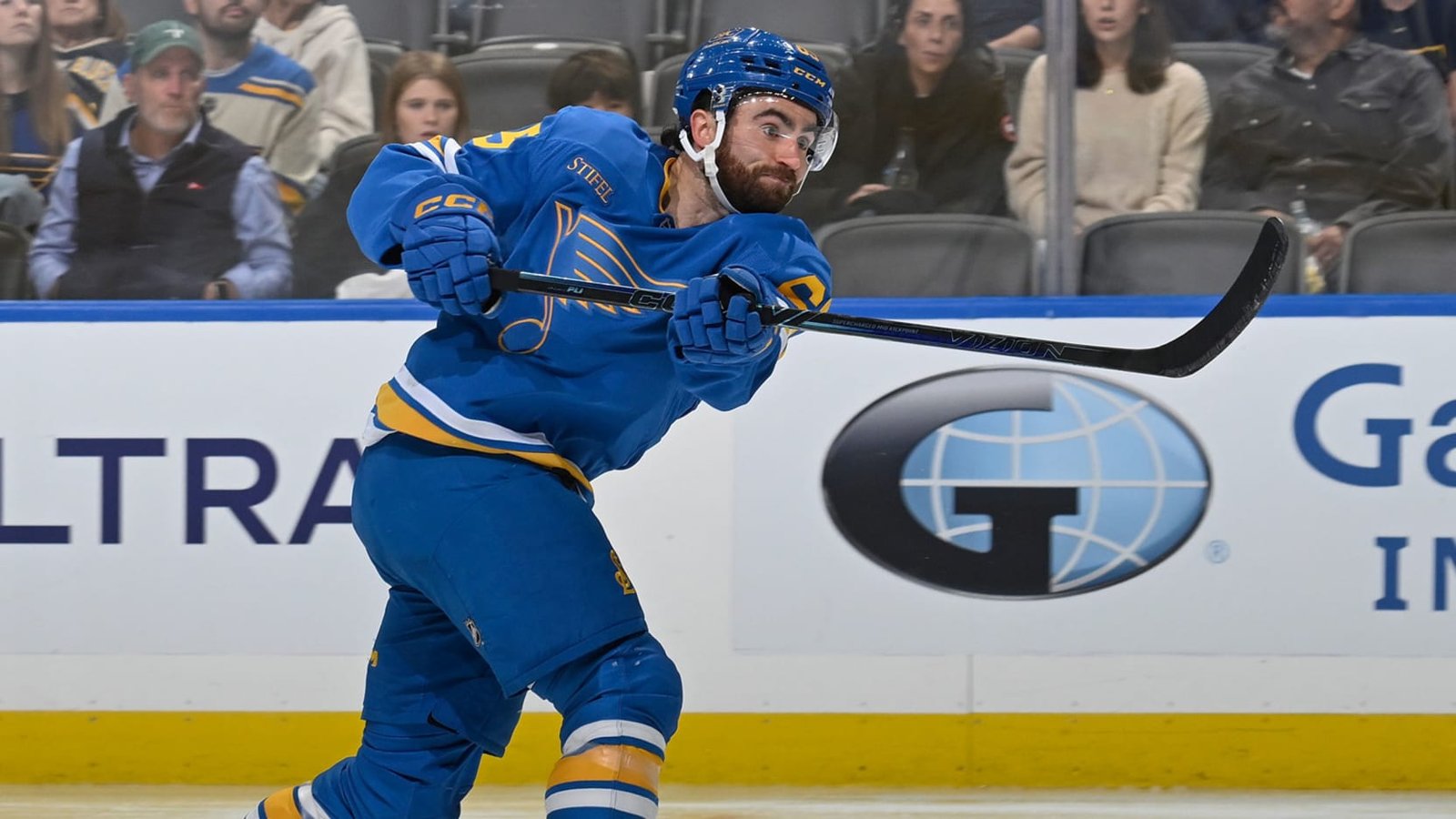Dillon Dube shooting the puck in a blue St. Louis Blues uniform.