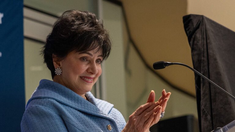 Gayle Benson applauds beside a lectern at Ochsner Health’s neuroscience institute ribbon cutting on October 1, 2026.
