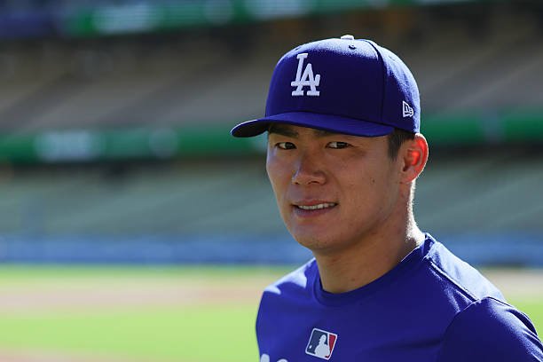 Yoshinobu Yamamoto wears a blue Dodgers cap and top at Dodger Stadium before NLDS Game 1
