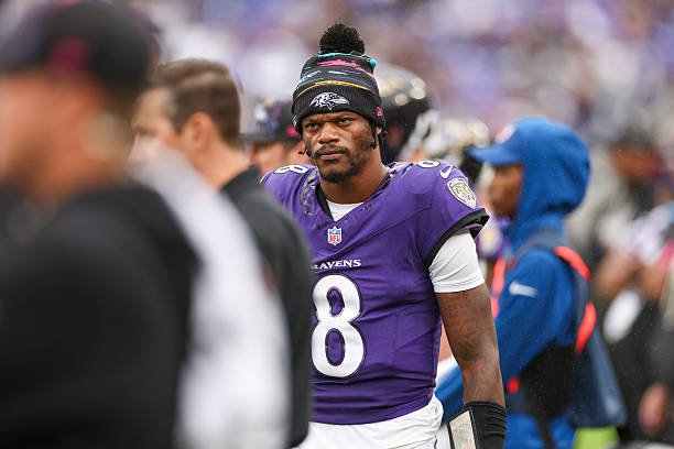 Lamar Jackson in a Ravens uniform and knit cap on the sideline against Tennessee.