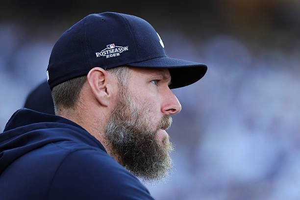 Chris Sale watches from the Braves dugout wearing a navy postseason cap