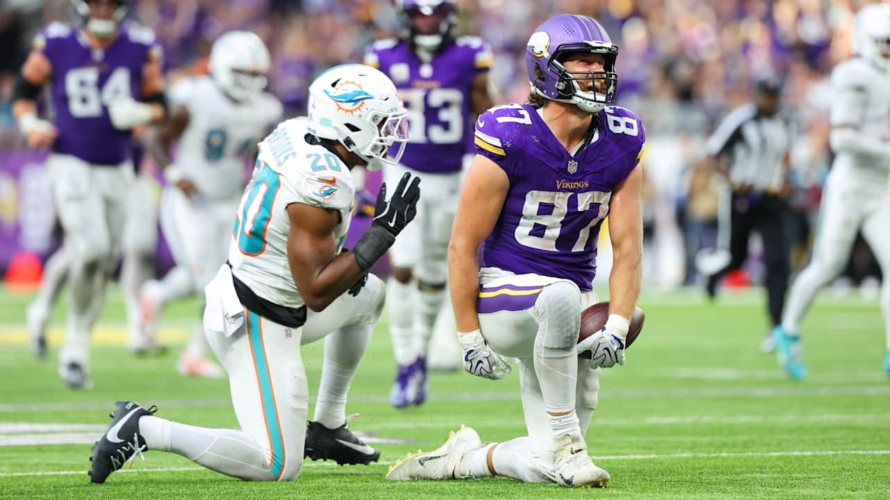 T.J. Hockenson kneels with the football beside a Miami Dolphins defender at U.S. Bank Stadium
