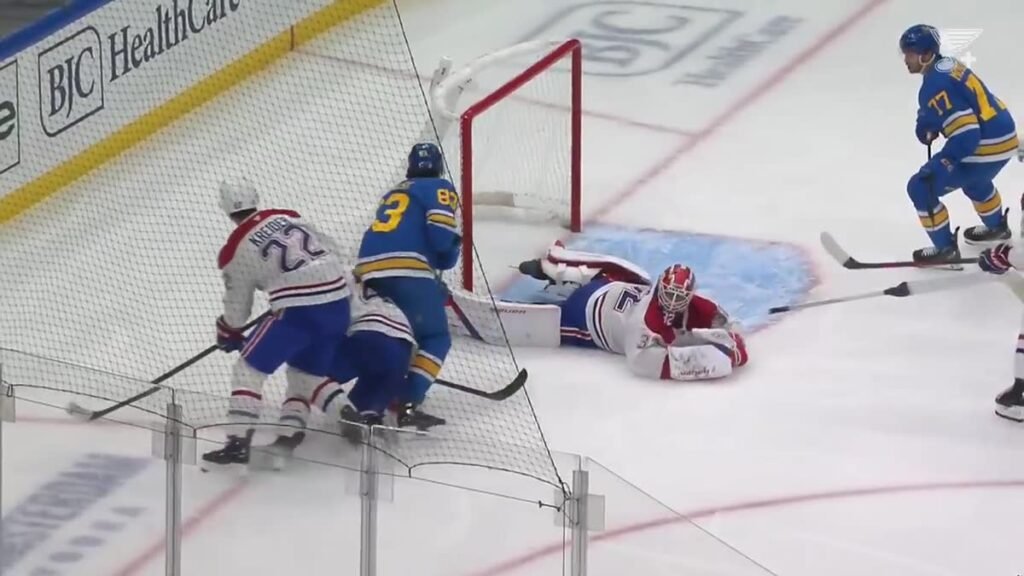 Montreal goalie Jacob Fowler stretches across the crease with a St. Louis player nearby.
