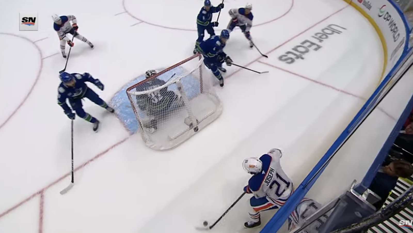 Mathieu Joseph, wearing Edmonton’s No. 21, controls the puck behind Vancouver’s net.