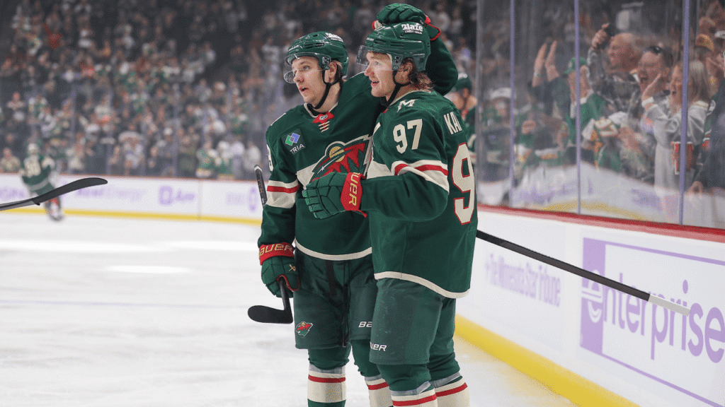 Kirill Kaprizov in a green Wild jersey celebrates beside the boards at Grand Casino Arena.
