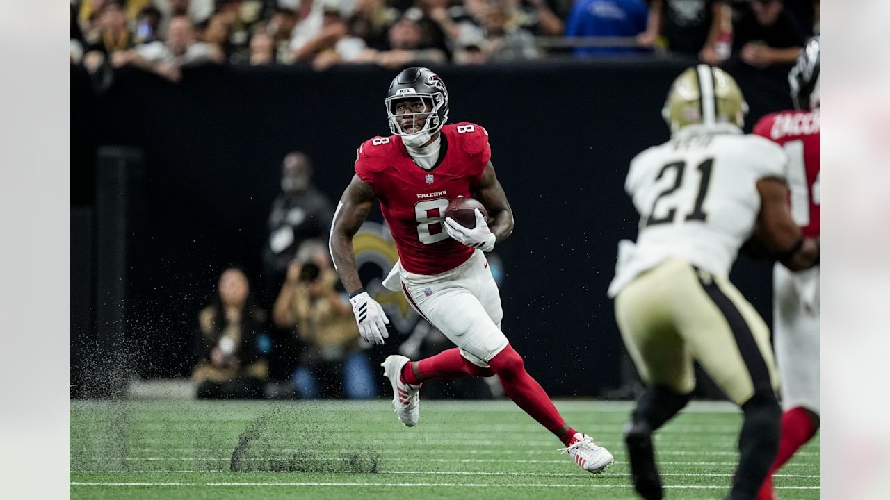 Falcons tight end Kyle Pitts carries the football as a Saints defender approaches.