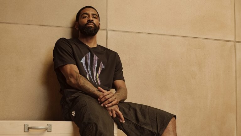 Kyrie Irving seated against a tan wall in an ANTA promotional portrait.