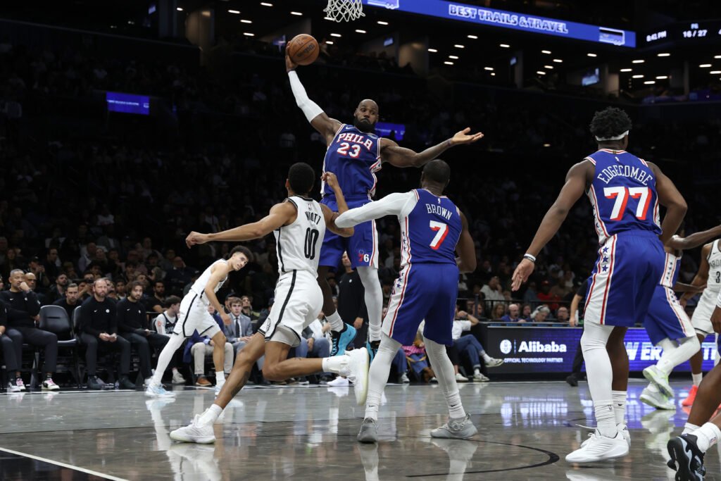 LeBron James reaches for a rebound in a blue Philadelphia 76ers uniform during a preseason game against Brooklyn.