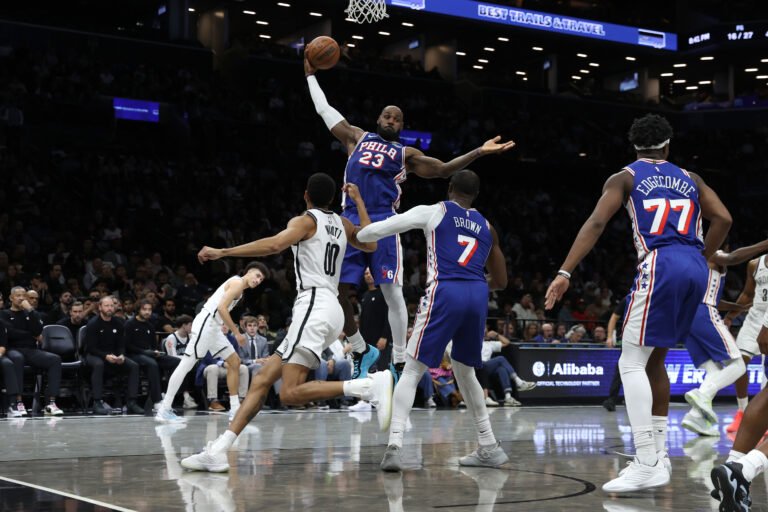 LeBron James reaches for a rebound in a blue Philadelphia 76ers uniform during a preseason game against Brooklyn.