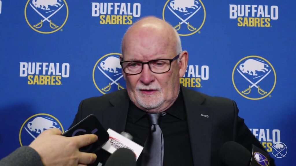 Lindy Ruff answers reporters’ questions in front of a Buffalo Sabres backdrop after the overtime loss in Montreal.